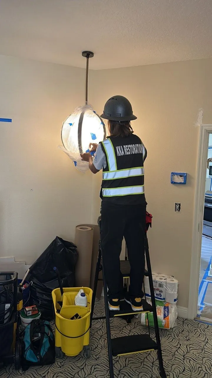 Commercial cleaning technician detailing a protected light fixture indoors