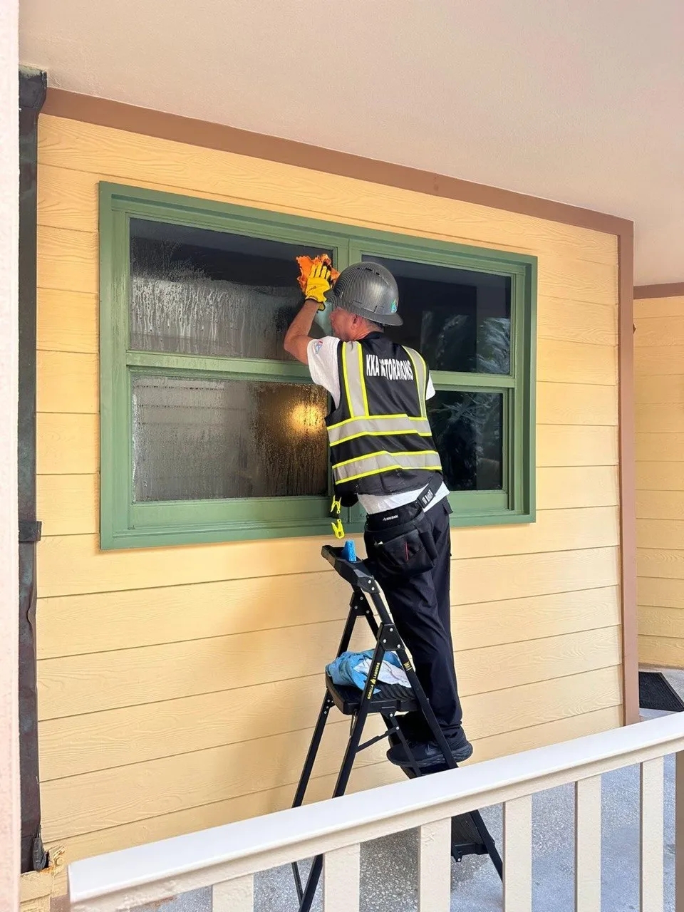 Commercial cleaning technician working on an exterior window and finish detail